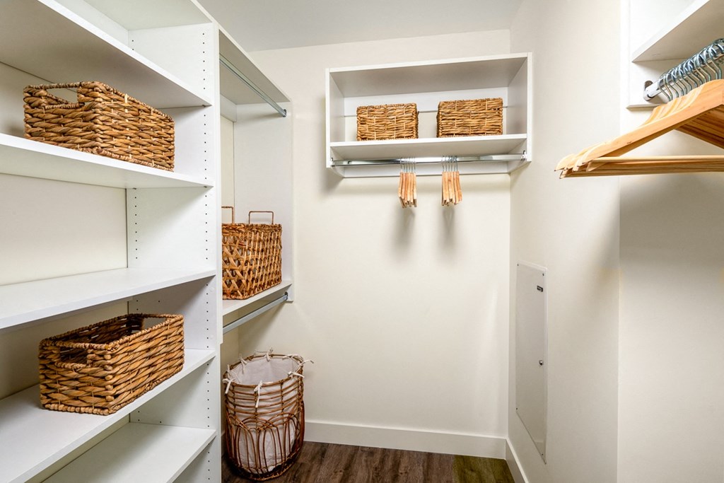 a walk in closet with wicker baskets and shelves
