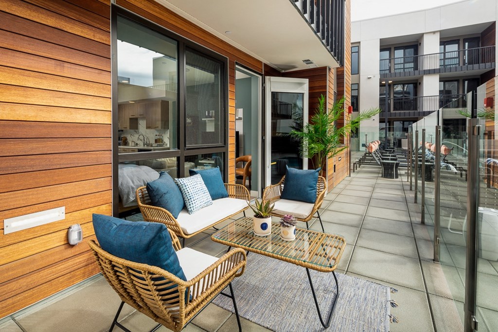 a patio with rattan chairs and a coffee table on a
