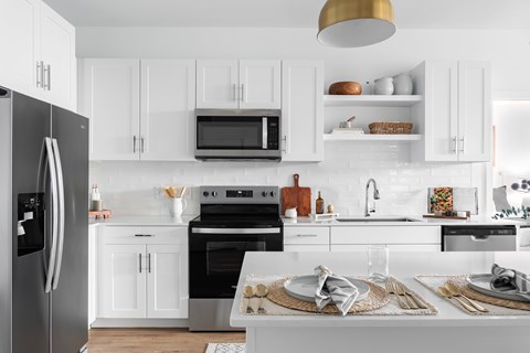 A modern kitchen with white cabinets and stainless steel appliances.