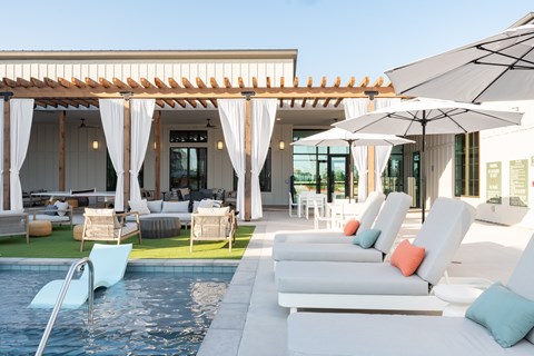 A poolside lounge area with white cushioned chairs and umbrellas.