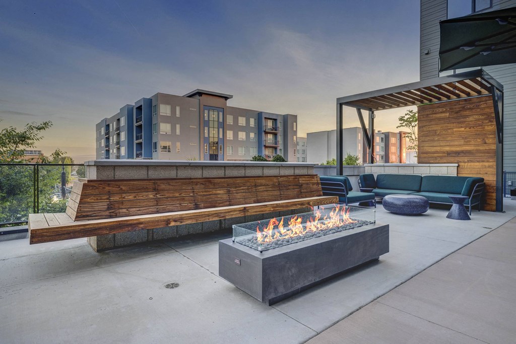 a lounge area with a fire pit and benches on a patio
