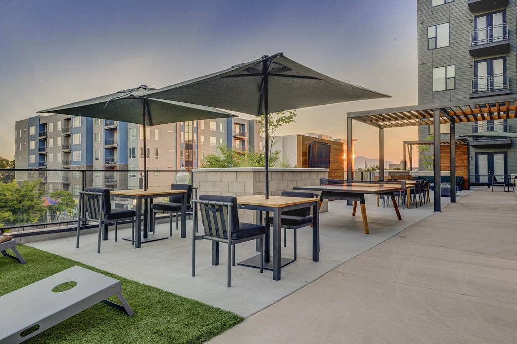 a rendering of an outdoor patio with tables and umbrellas at dusk