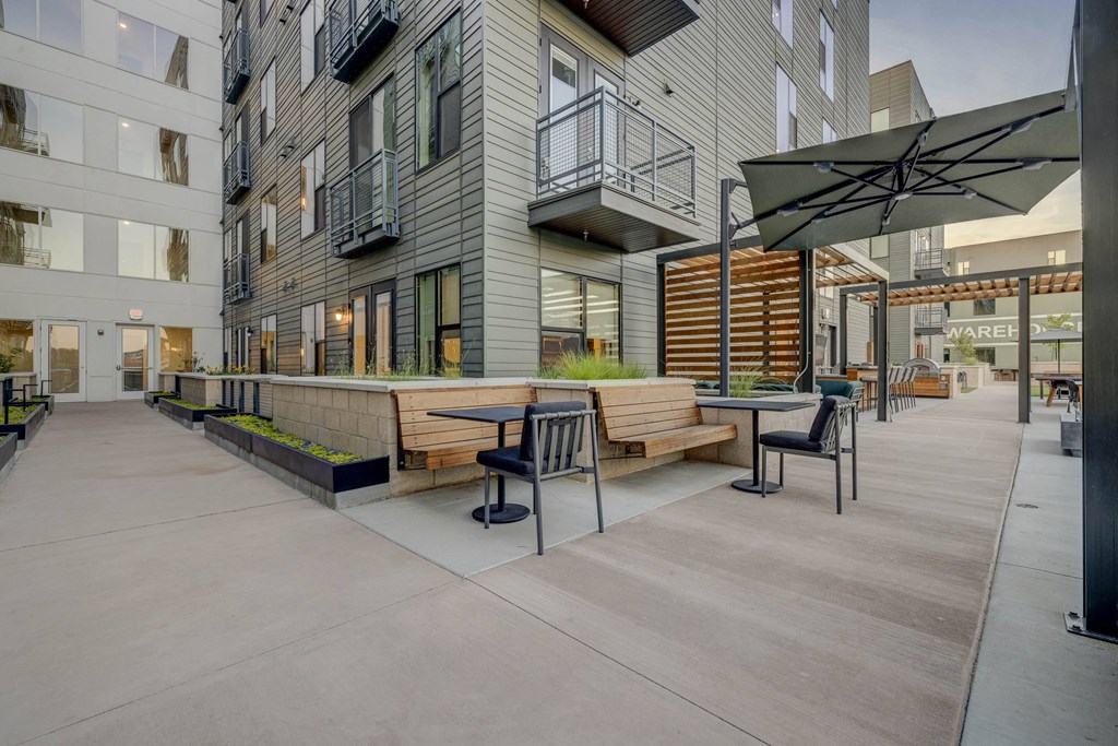 an outdoor patio area with benches and tables in front of buildings