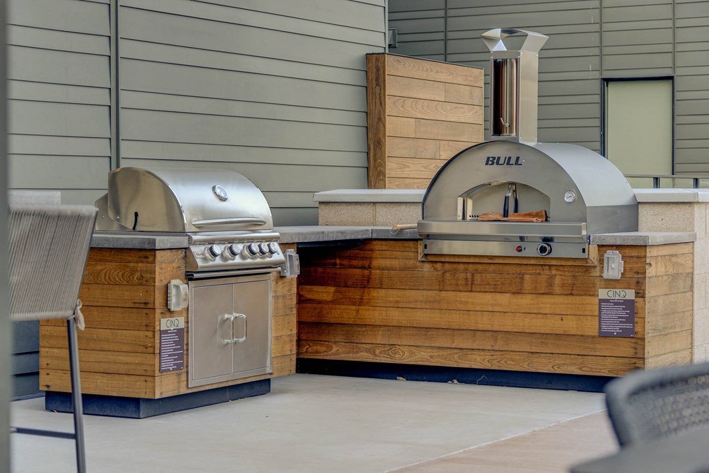 a bbq area with two stainless steel grills and a wooden grill