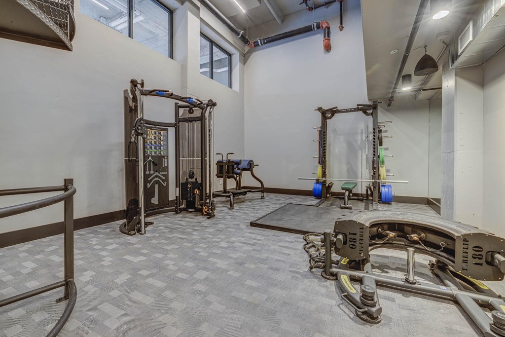 a workout room with weights and machines in a room with windows