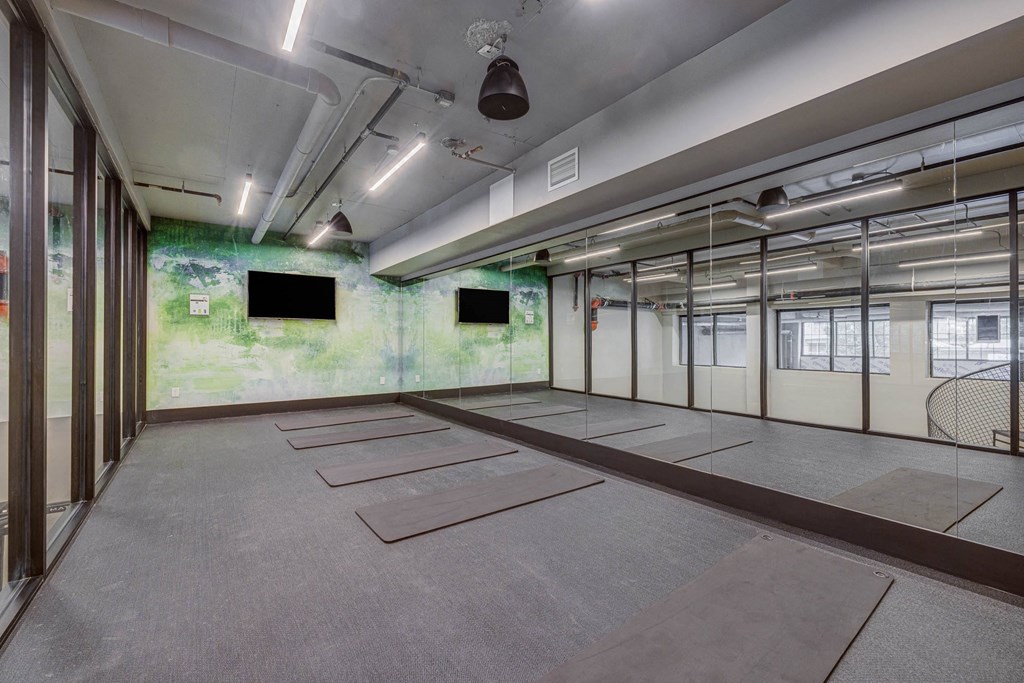 an empty room with mats on the floor and televisions on the wall