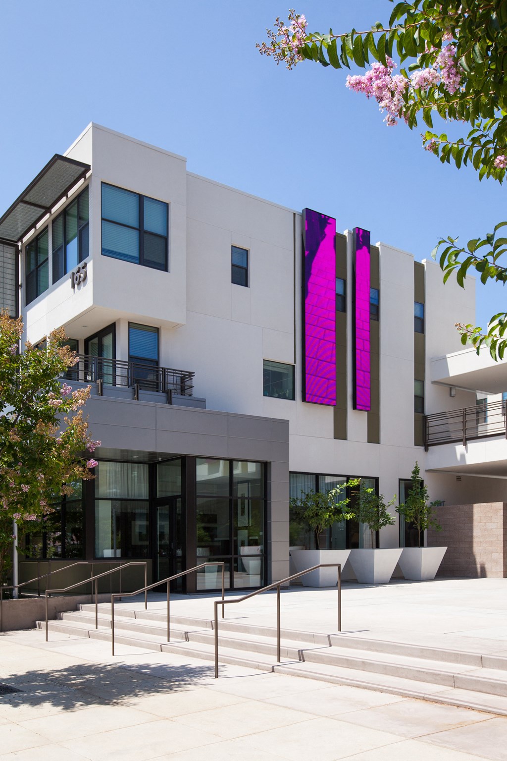 a white building with pink banners and trees