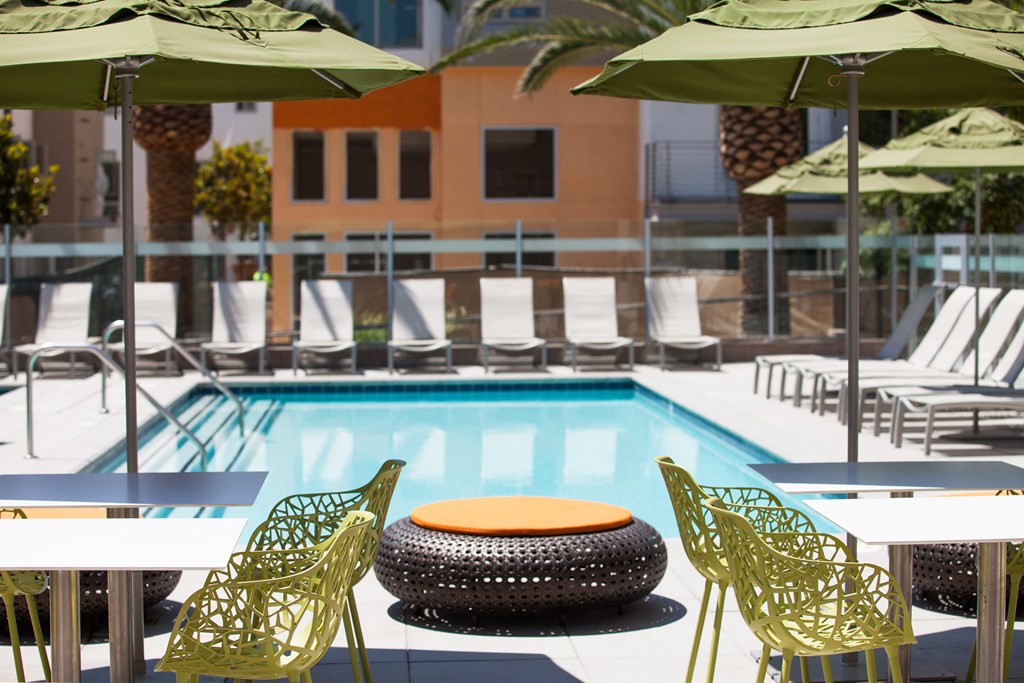 a pool with green chairs and umbrellas