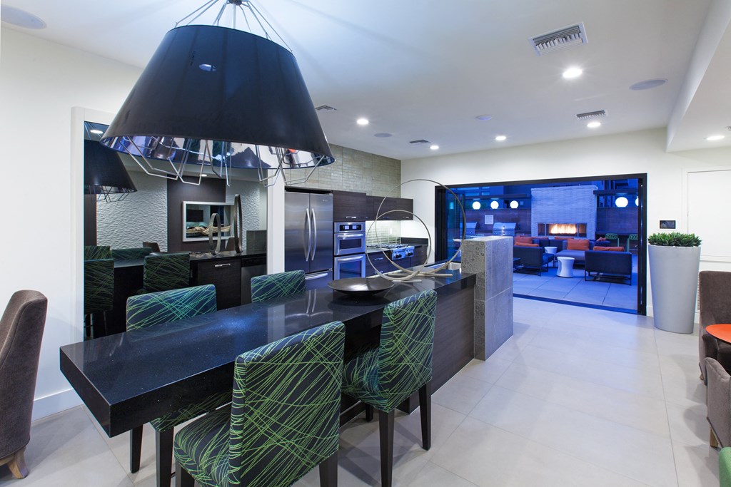 a kitchen with a long black island with a black countertop and a black chandelier