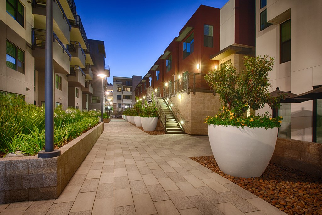 a picture of an apartment complex at night with the lights on and plants in the planters