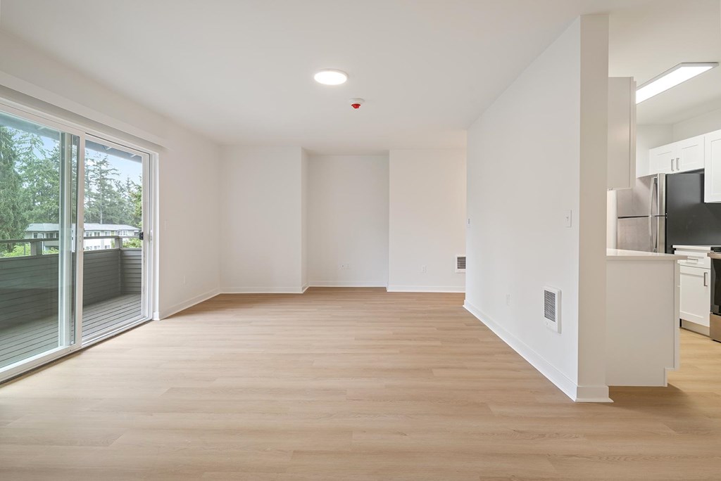 A spacious, empty room with wooden floors and white walls.