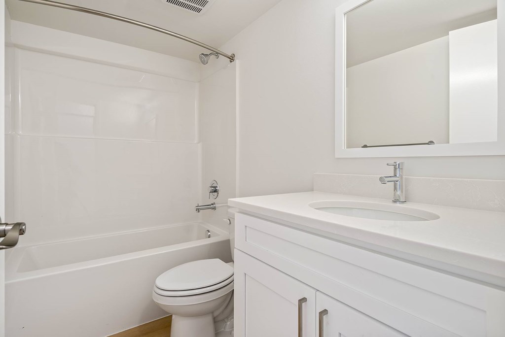 A white bathroom with a toilet, sink, and bathtub.