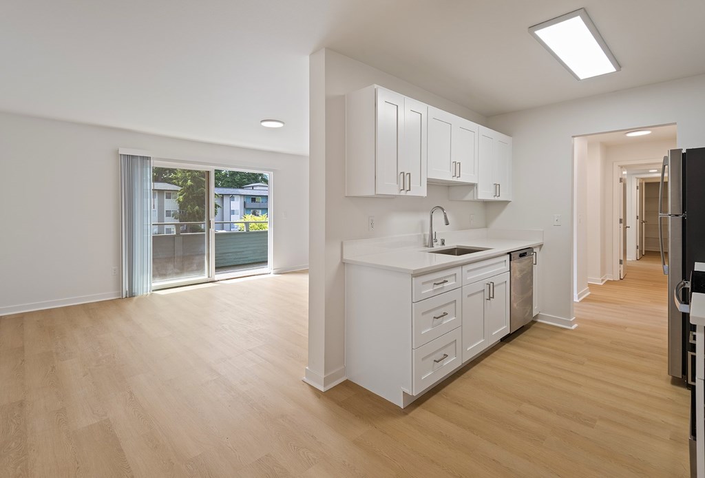 A kitchen with white cabinets and a black fridge.