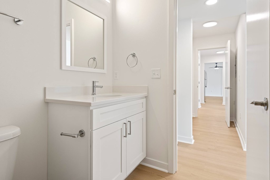 A white bathroom with a sink, mirror, and toilet.