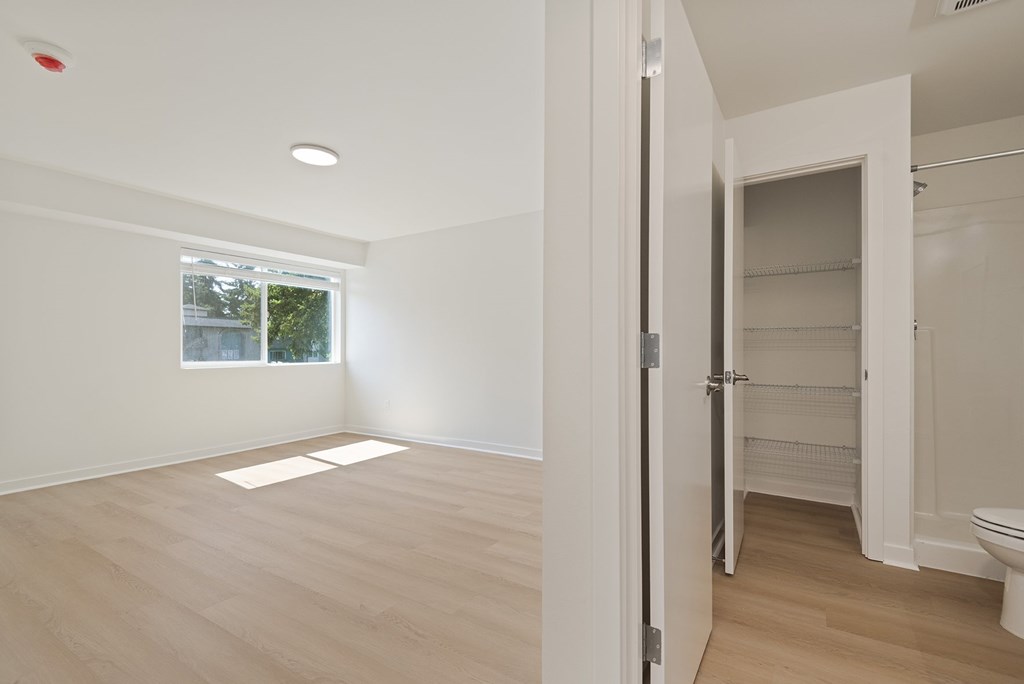 A white room with a window and a door leading to a bathroom.
