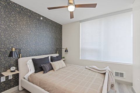a bedroom with a dark accent wall and a ceiling fan