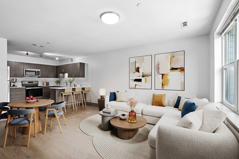 A modern living room with a dining area and kitchen in the background.