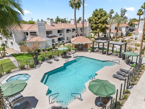 A large swimming pool surrounded by lounge chairs and umbrellas.