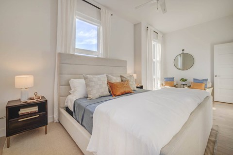 a white bedroom with a large bed and a window