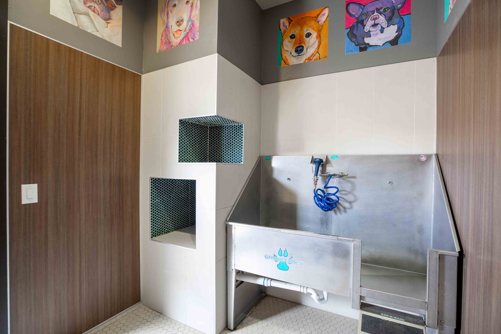 a bathroom with a stainless steel sink and paintings on the wall