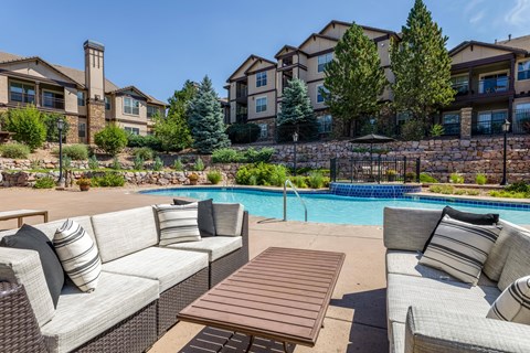A poolside patio with a couch, table, and chairs.