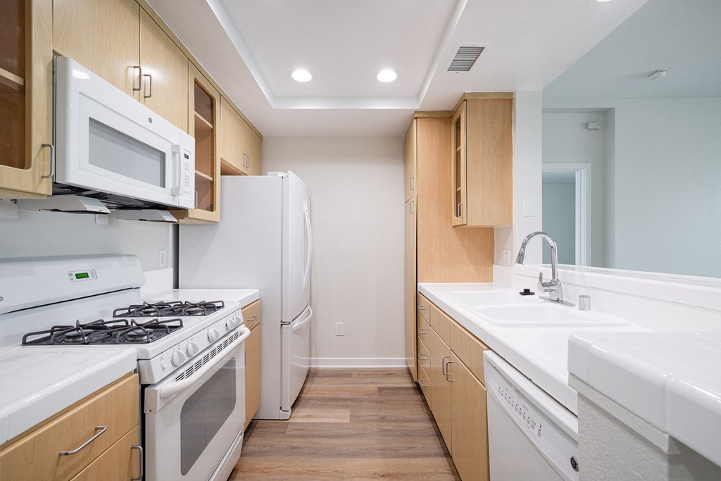 A kitchen with white appliances and wooden cabinets.