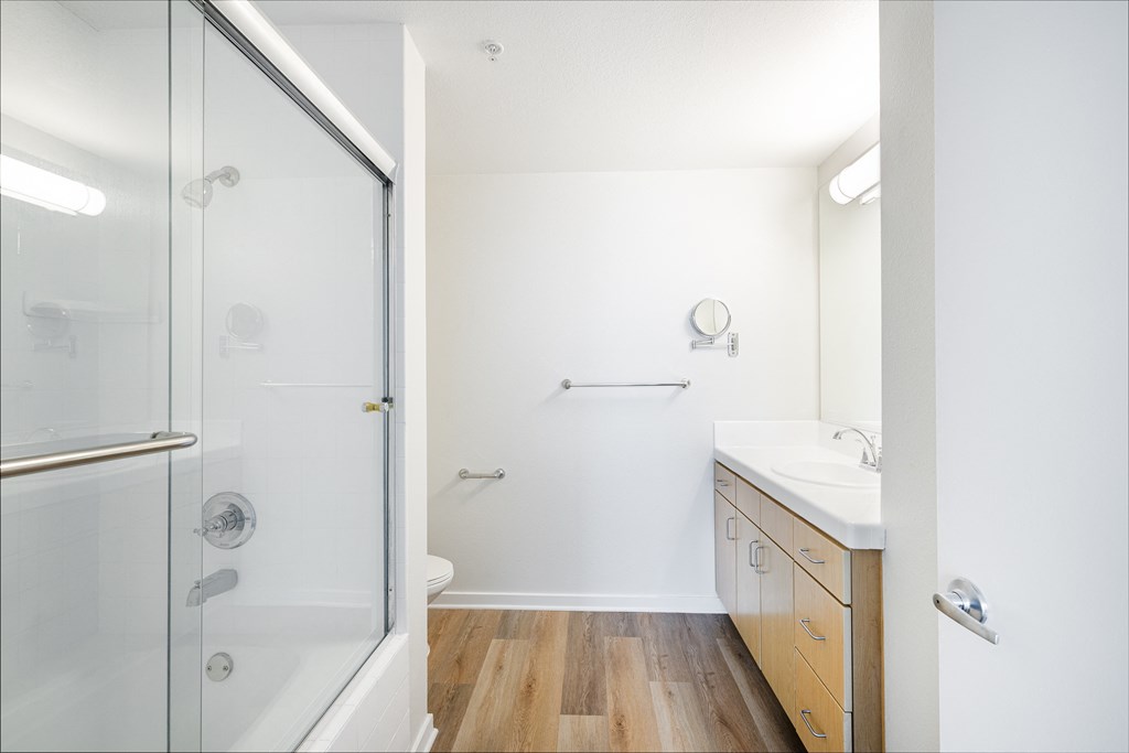 A white bathroom with a walk in shower and a sink.