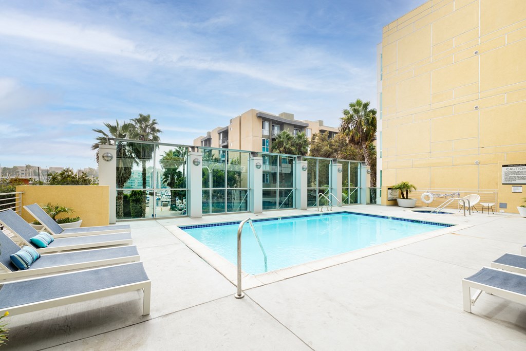 A pool surrounded by sun loungers and a yellow wall.