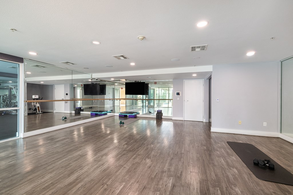 A spacious room with wooden flooring and a ballet barre.