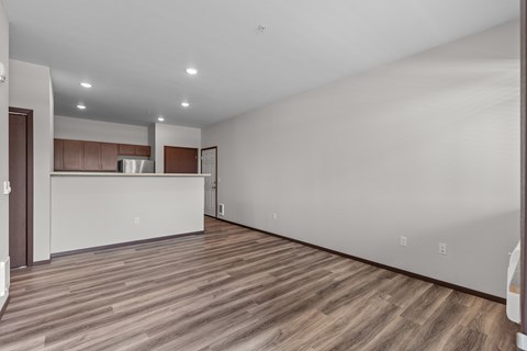 A spacious room with wooden flooring and white walls.