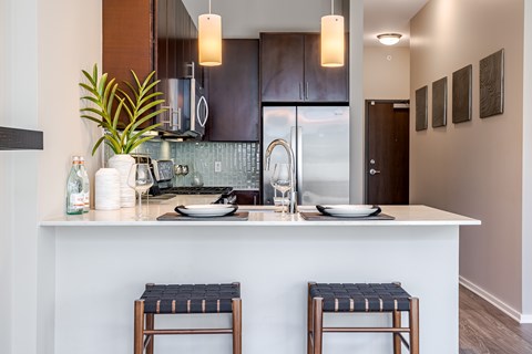 A kitchen with a white counter top and two stools.