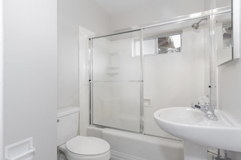 a white bathroom with a shower and a sink