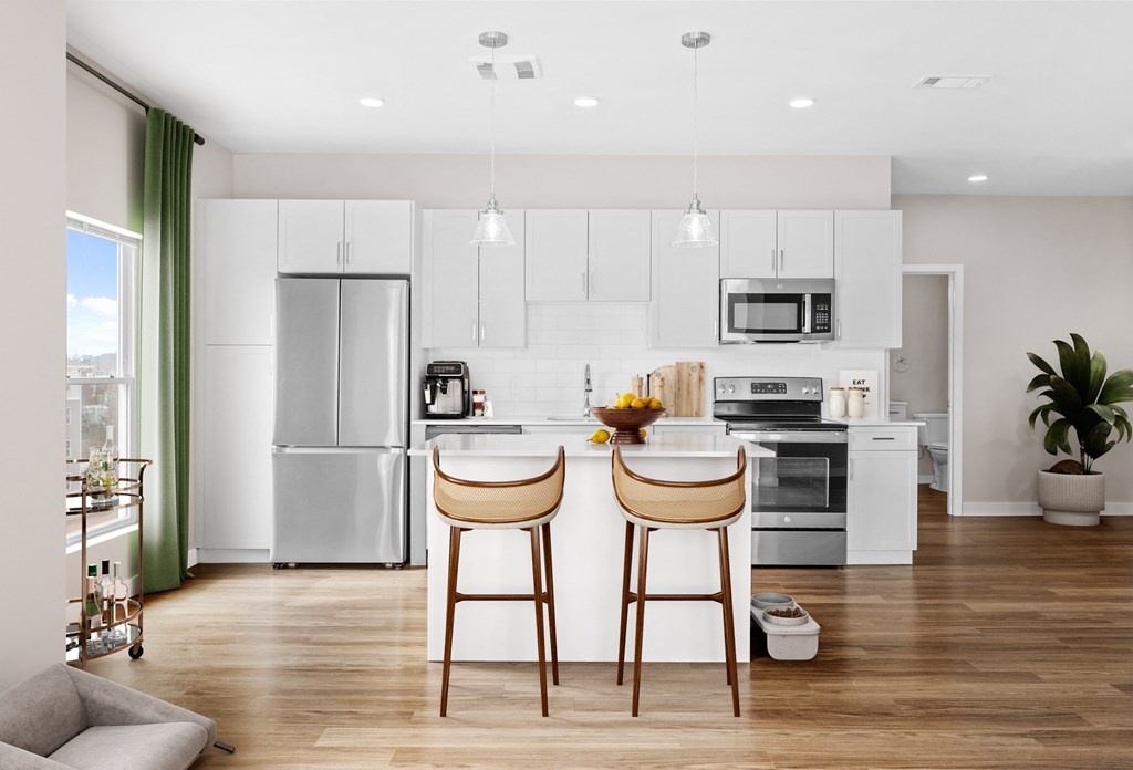 a kitchen with white cabinets and a island with two chairs