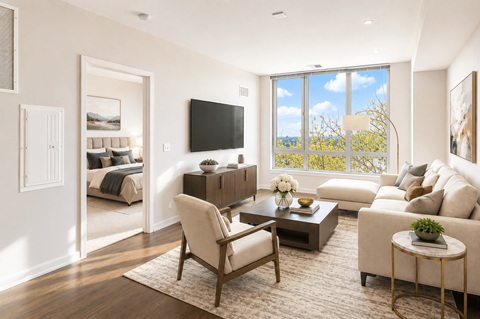 A living room with a large window, a sofa, a chair, a coffee table, and a flat-screen TV.