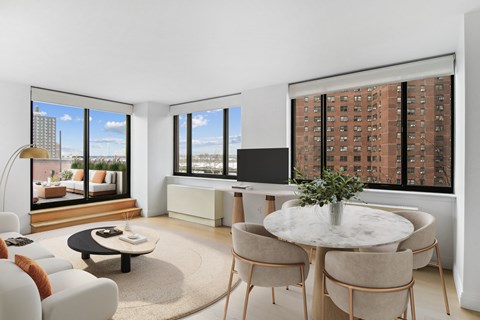 an open living room with a table and chairs and a view of a skyscraper