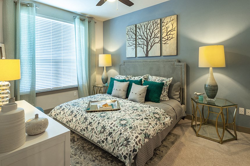 a bedroom with a bed and lamps and a painting on the wall