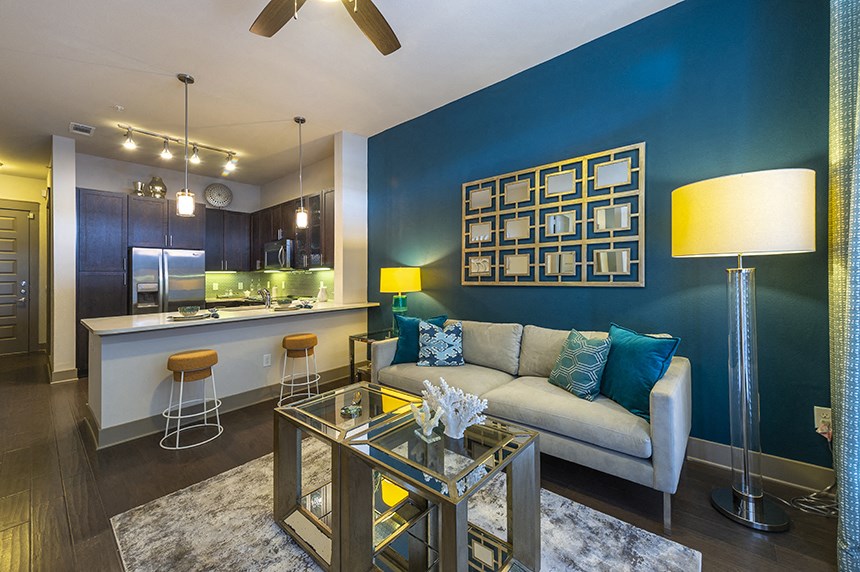 a living room with a blue accent wall and a kitchen