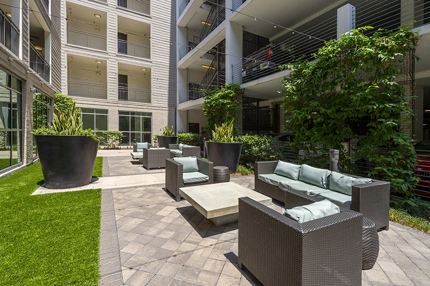 a patio with couches and chairs in front of a building