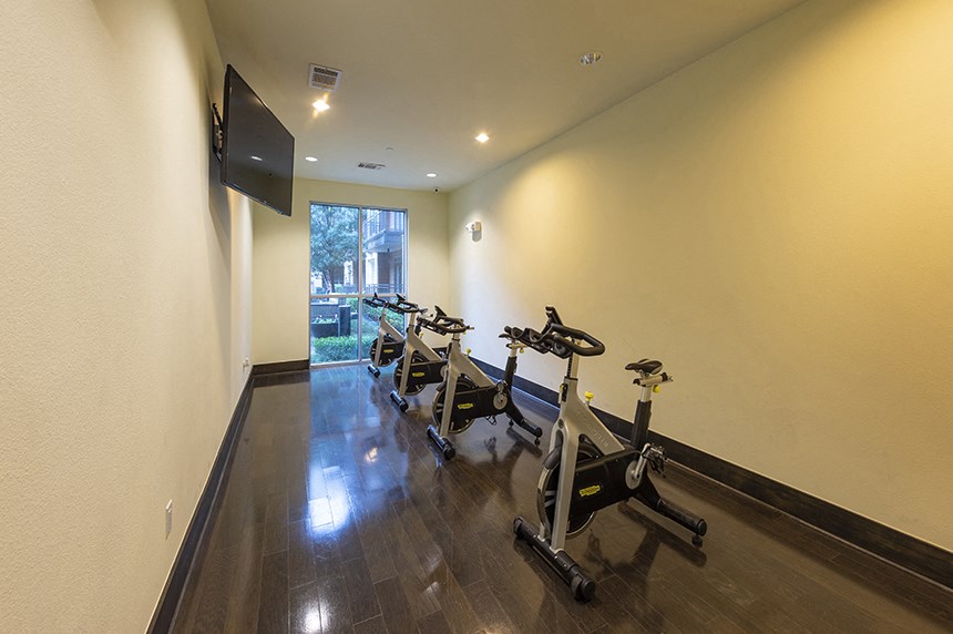 a gym with several exercise bikes and a television