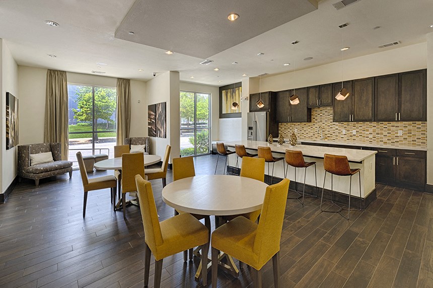 a community room with tables and chairs and a kitchen