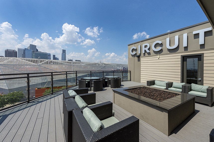 a rooftop patio with a fire pit and seating area with a view of the city