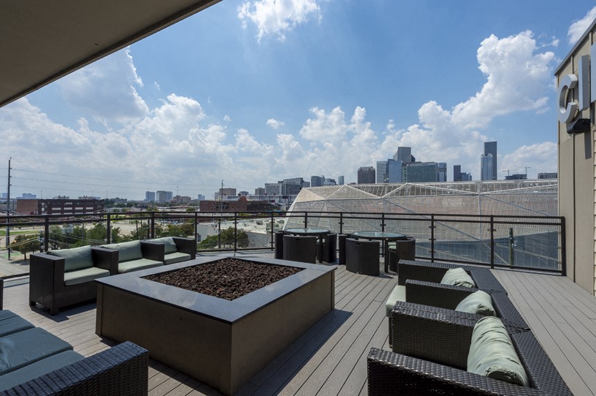 a rooftop deck with furniture and a view of the city