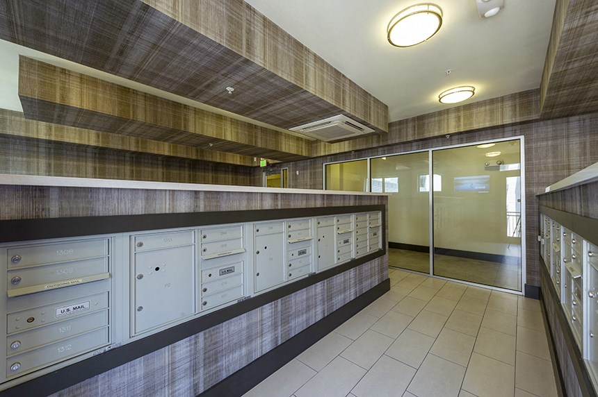 the mail room in the lobby of a building with mailboxes and a long counter