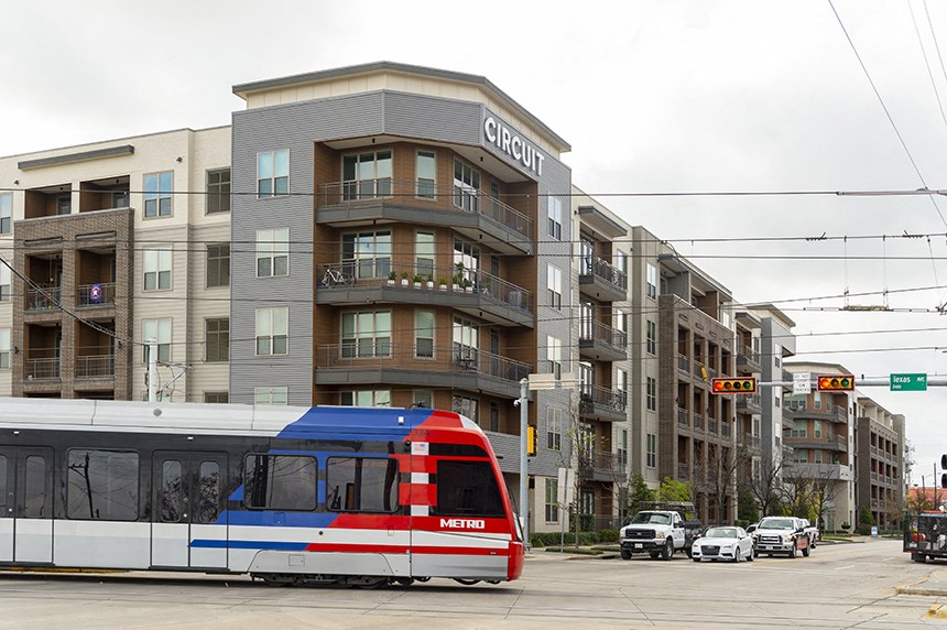 a city bus driving past an apartment building on a city street