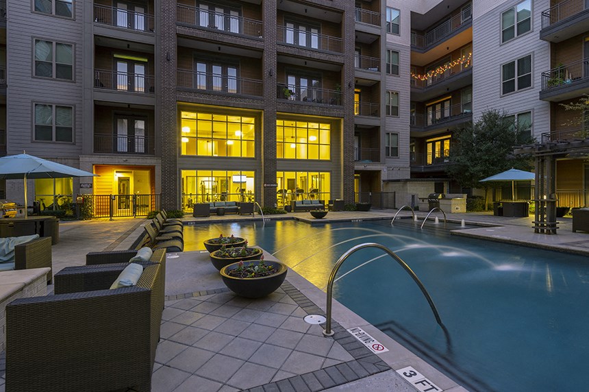 a swimming pool at night in front of a building