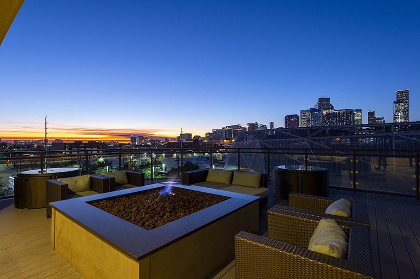 a rooftop terrace with a fire pit and a view of the city at night