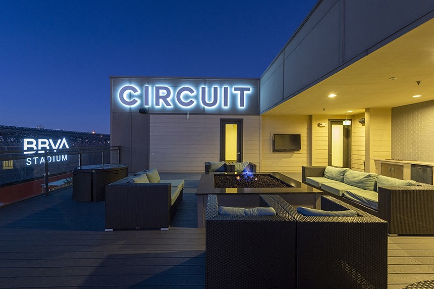 a lounge area on the roof of a building with a nightclub sign on the facade