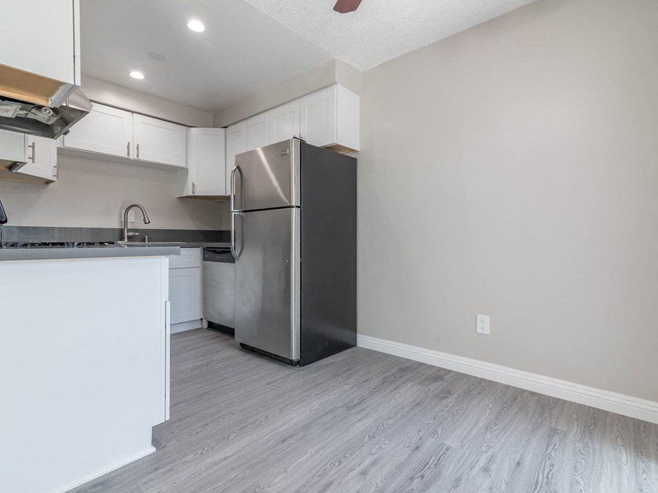 a white kitchen with a stainless steel refrigerator at Citrus Court Apartments, Whittier, CA, 90606