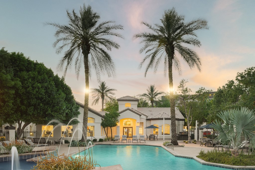 a swimming pool with palm trees and a building in the background