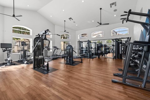 A gym with a variety of equipment including treadmills, weights, and exercise machines.